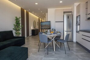 Una sala de estar moderna con comedor, sofá, una planta y un cuadro en la pared.