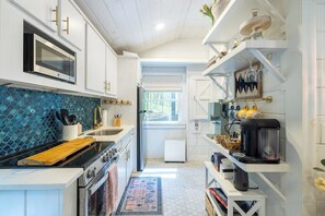 A modern kitchen with white cabinetry, a blue tiled backsplash, and a coffee machine on a shelf. - Wellness Lodge - Sauna, cold plunge, jacuzzi (Morganton)