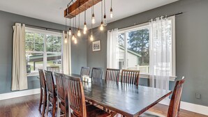 Comedor con una gran mesa de madera, seis sillas y lámparas colgantes.