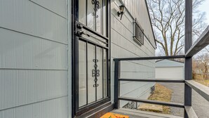 A wooden deck with a metal railing, a door with decorative glass panels, and a small garden area with a tree and a mailbox. - 6 Mi to Downtown Columbus: Quiet Home w/ Yard (Columbus)