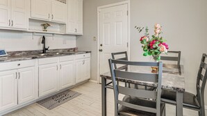 A kitchen with white cabinets, a marble countertop, and a dining table with chairs. - 6 Mi to Downtown Columbus: Quiet Home w/ Yard (Columbus)
