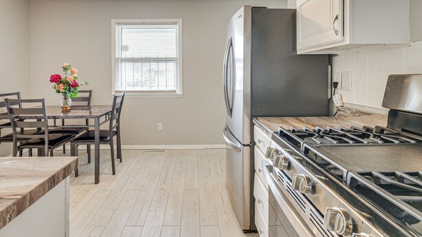 A modern kitchen with a stainless steel refrigerator, a gas stove, and a dining area with a table and chairs. - 6 Mi to Downtown Columbus: Quiet Home w/ Yard (Columbus)