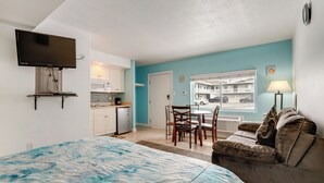 A bedroom with a bed, a TV mounted on the wall, a kitchenette, a dining area, and a window with a view of the outside. - Walk to Shore! Family Haven w/ Pool in Ocean City (Ocean City)