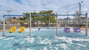 A playground with swings and a blue rubberized surface. - Walk to Shore! Family Haven w/ Pool in Ocean City (Ocean City)