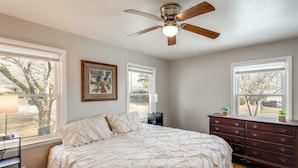 A bedroom with a bed, a ceiling fan, a dresser, and two windows. - Near Medical Centers & Fort Jackson! Quiet Home (Columbia)