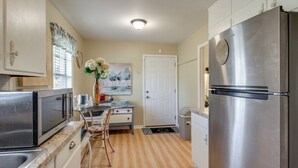 Una cocina compacta con un refrigerador de acero inoxidable, un microondas y un comedor con mesa y sillas.