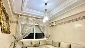 A modern living room with a sectional sofa, a wooden coffee table, and a ceiling light fixture. - Apartment 4 min Tgv and Beach (Tanger)