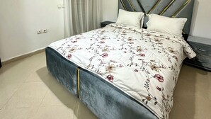 A bedroom with a bed, a nightstand, a modern chandelier, and a window with sheer curtains. - Apartment 4 min Tgv and Beach (Tanger)