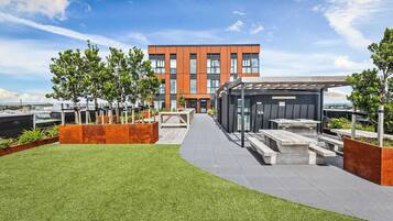 A modern building with a flat roof terrace, outdoor seating area, and a clear view of the sky.