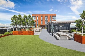 A modern building with a flat roof terrace, outdoor seating area, and a clear view of the sky. - Modern High Rise w/ Parking by Zodiak Stays (Auckland)