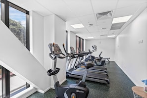 A gym with treadmills, ellipticals, and a mirrored wall. - Modern High Rise w/ Parking by Zodiak Stays (Auckland)