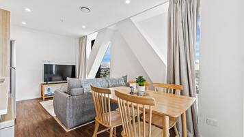 A modern living room with a dining table, sofa, and TV.