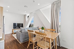 Un salon moderne avec une table à manger, un canapé et un téléviseur.