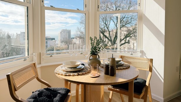 Un comedor con una mesa redonda, sillas y vistas a la ciudad a través de amplios ventanales.
