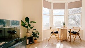 Una sala de estar moderna con televisor, mesa de comedor, sillas y plantas en macetas.