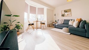 Una sala de estar moderna con un sofá, una mesa de comedor, sillas y un televisor.