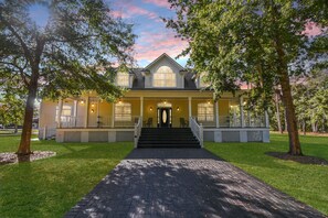 A two-story house with a front porch, a central entrance, and a brick pathway leading to the door. - All-in-one Luxury Escape Three Properties, Event Hosting, Private Pond & Full Gym (Jacksonville)