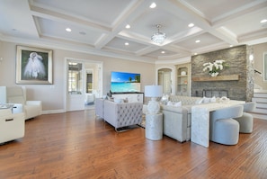 A spacious living room with a large sectional sofa, a television, and a stone accent wall. - All-in-one Luxury Escape Three Properties, Event Hosting, Private Pond & Full Gym (Jacksonville)