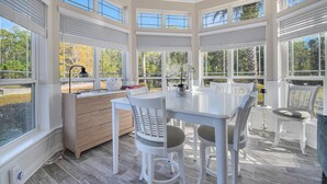 A bright, spacious sunroom with large windows, a wooden table, and white chairs. - All-in-one Luxury Escape Three Properties, Event Hosting, Private Pond & Full Gym (Jacksonville)