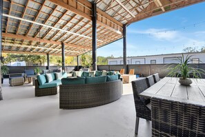 An outdoor patio area with wicker furniture, including sofas and chairs, under a wooden pergola with a metal roof. - All-in-one Luxury Escape Three Properties, Event Hosting, Private Pond & Full Gym (Jacksonville)