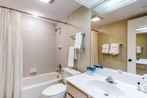 Une salle de bain avec une baignoire, des toilettes, un lavabo et un grand miroir.