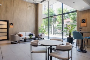 Ein modernes Interieur mit einer Couch, Sesseln, einem runden Tisch und einer Kaffeestation.