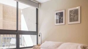 A modern hotel room with a large bed, a view of the city, and two framed pictures on the wall. - Modern 2BR2BA Apartment in Downtown Santiago (Santiago)