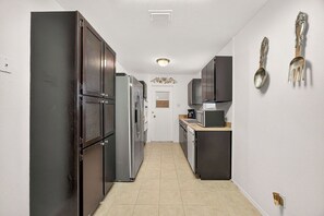 A narrow kitchen with dark cabinets, a microwave, and a refrigerator. - Spacious 4-bedroom house in Arlington close to the Entertainment District (Arlington)