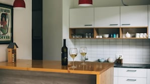 Een keuken met houten werkbladen, witte kastjes en rode hanglampen.