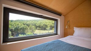 Un dormitorio con un ventanal que ofrece vistas a un área boscosa.