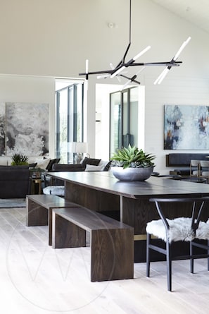 A modern kitchen with a large island, dark wood flooring, and a contemporary light fixture.