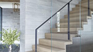 Een moderne trap met glazen balustrades en houten treden.