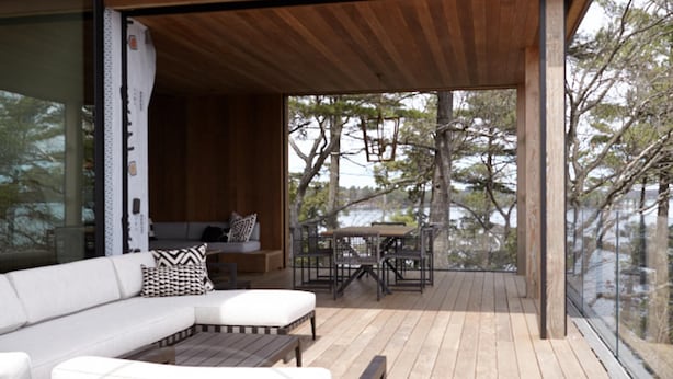 Een modern terras buiten met houten vloer, een loungeset en een eettafel.