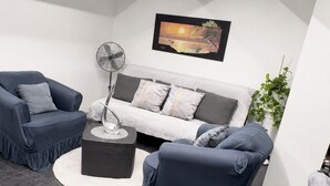 A modern living room with a sofa, two armchairs, a coffee table, a floor lamp, and a wall-mounted TV. - Le petit luxe urbain (Bussigny)