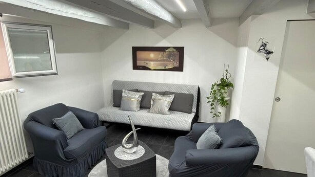 A modern living room with a sofa, two armchairs, a coffee table, and a radiator. - Le petit luxe urbain (Bussigny)