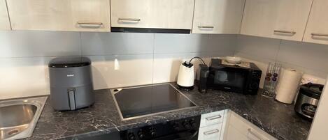 A modern kitchen with stainless steel cabinets, a black countertop, a built-in oven, and a dishwasher.