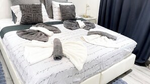 A modern bedroom with a large bed, a framed picture on the wall, and a nightstand. - Le petit luxe urbain (Bussigny)