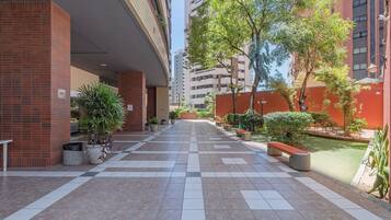 Une cour avec un chemin bordé de carreaux, des plantes en pot et un banc.