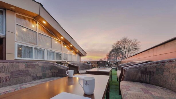Uma área de estar moderna ao ar livre, com mesa, cadeiras e vista para o pôr do sol.
