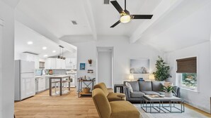 Een moderne woonkamer met een bank, salontafel en een eethoek met tafel en stoelen.