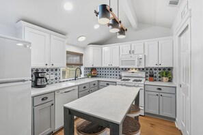 A modern kitchen with white cabinets, a central island, and a microwave. - Lazy Day Getaway - 5 min walk to the square - Historic home (Georgetown)