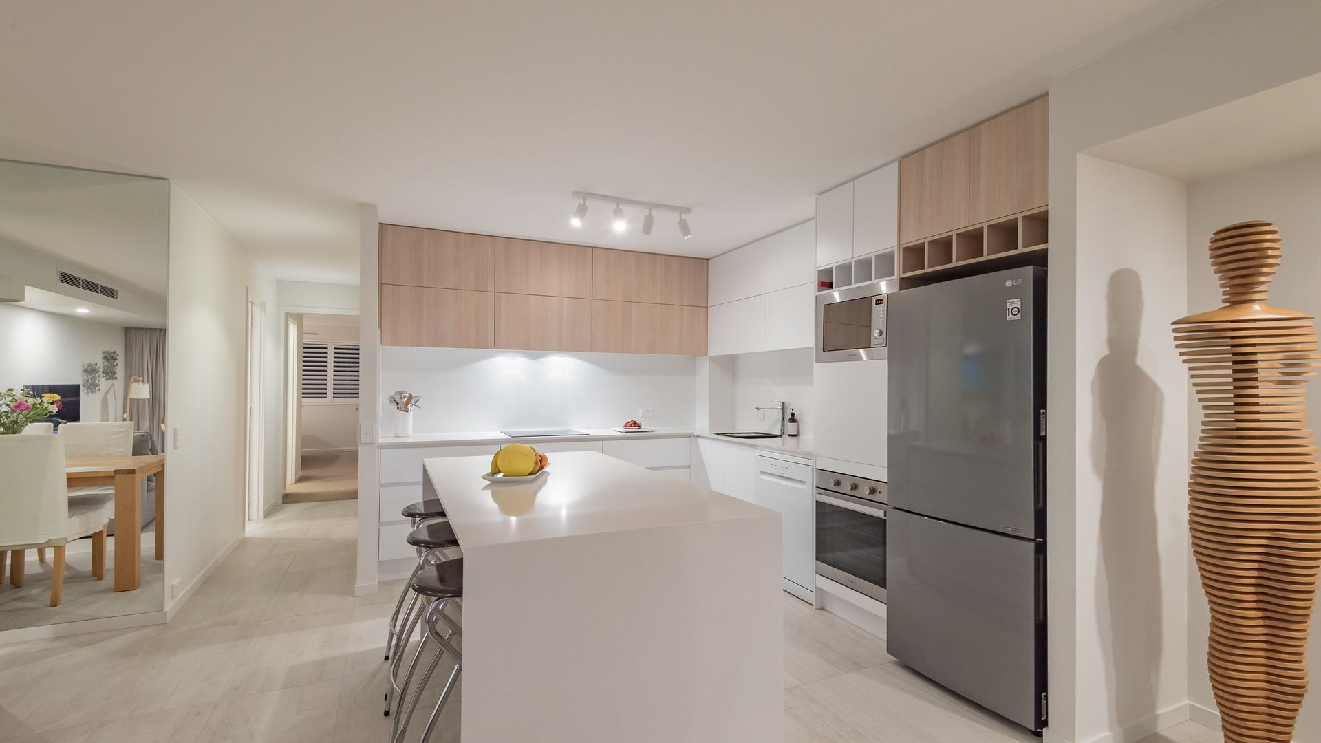 Una cocina moderna con armarios blancos, un refrigerador de acero inoxidable y una isla central.
