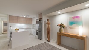 Una cocina moderna con muebles blancos, electrodomésticos de acero inoxidable y una isla central.