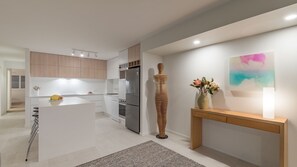 A modern kitchen with white cabinetry, stainless steel appliances, and a central island. - 4 The Anchorage - riverside living (Noosaville)
