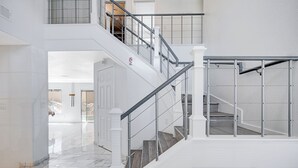 A multi-level interior with a staircase, marble flooring, and white walls.