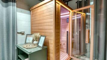 Uma sala de sauna com um banco de madeira, um certificado emoldurado e um pequeno vaso com plantas secas.