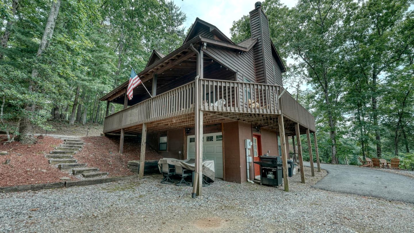A cabin with a porch, a covered outdoor seating area, and a grill.