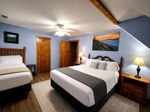 Ein Schlafzimmer mit zwei Betten, Holz-Kopfteilen, einem Deckenventilator und einem Bild an der Wand.