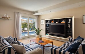 A living room with a large TV, a pool view, and striped sofas. - Beautiful home in Vabriga (Vabriga)
