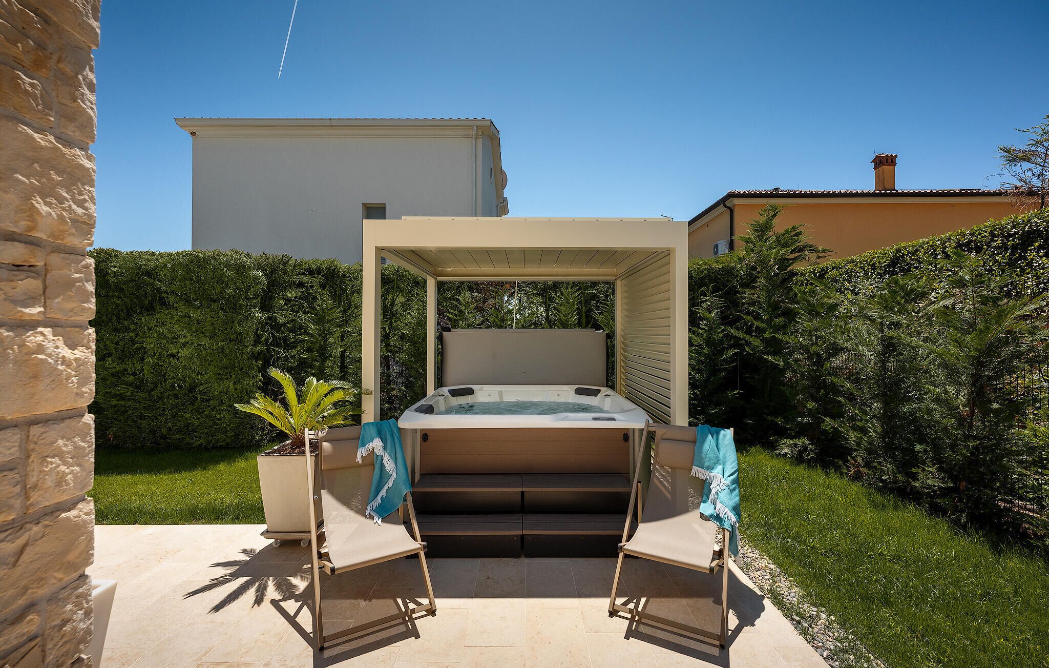 Un bain à remous avec deux sièges, une pergola et un mur en pierre.